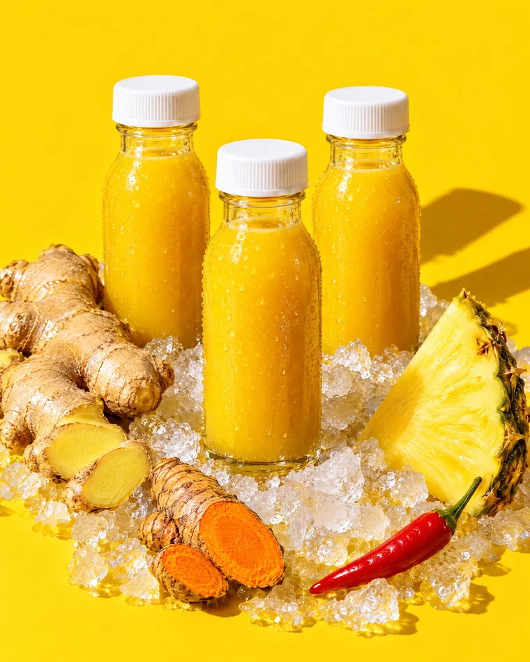 Three ginger shots on ice with fresh ginger, turmeric, pineapple and a cayenne pepper